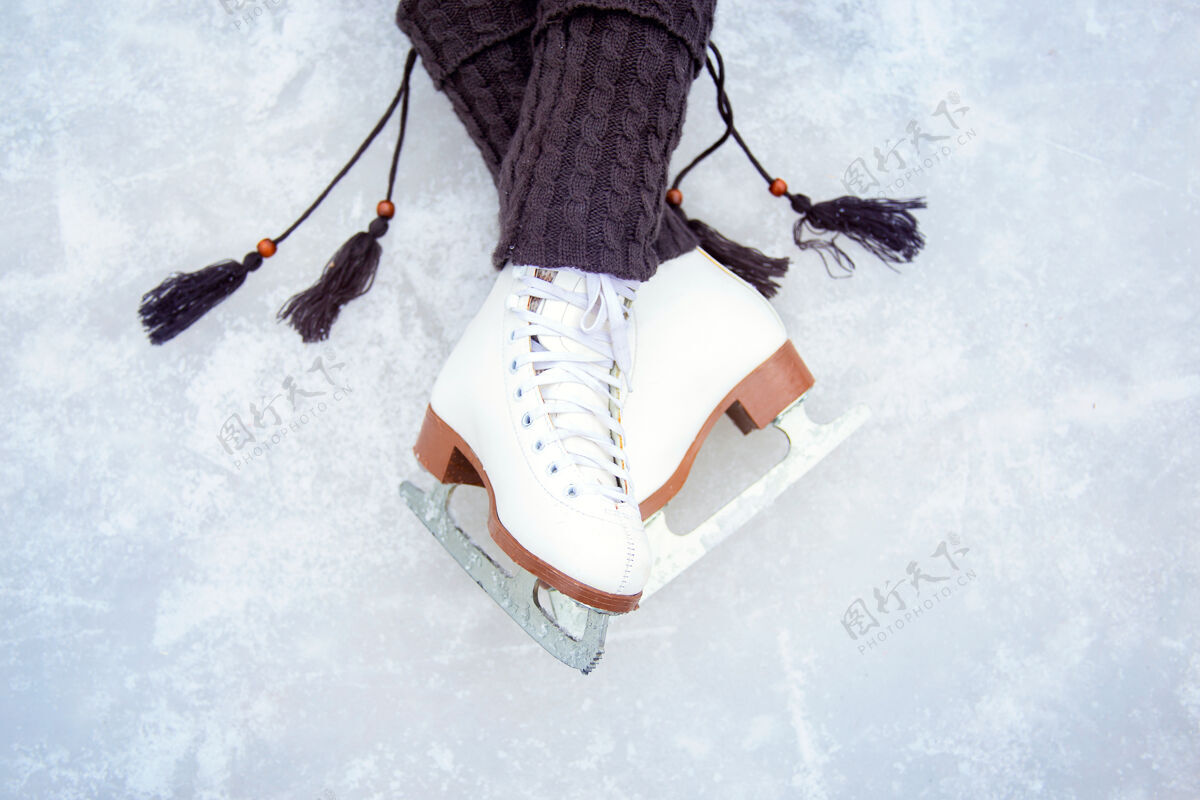 欢乐穿着白色花样滑冰鞋的腿溜冰场上腿的美丽姿势带流苏和经典花样滑冰鞋的温暖针织暖腿裤乐趣谎言溜冰