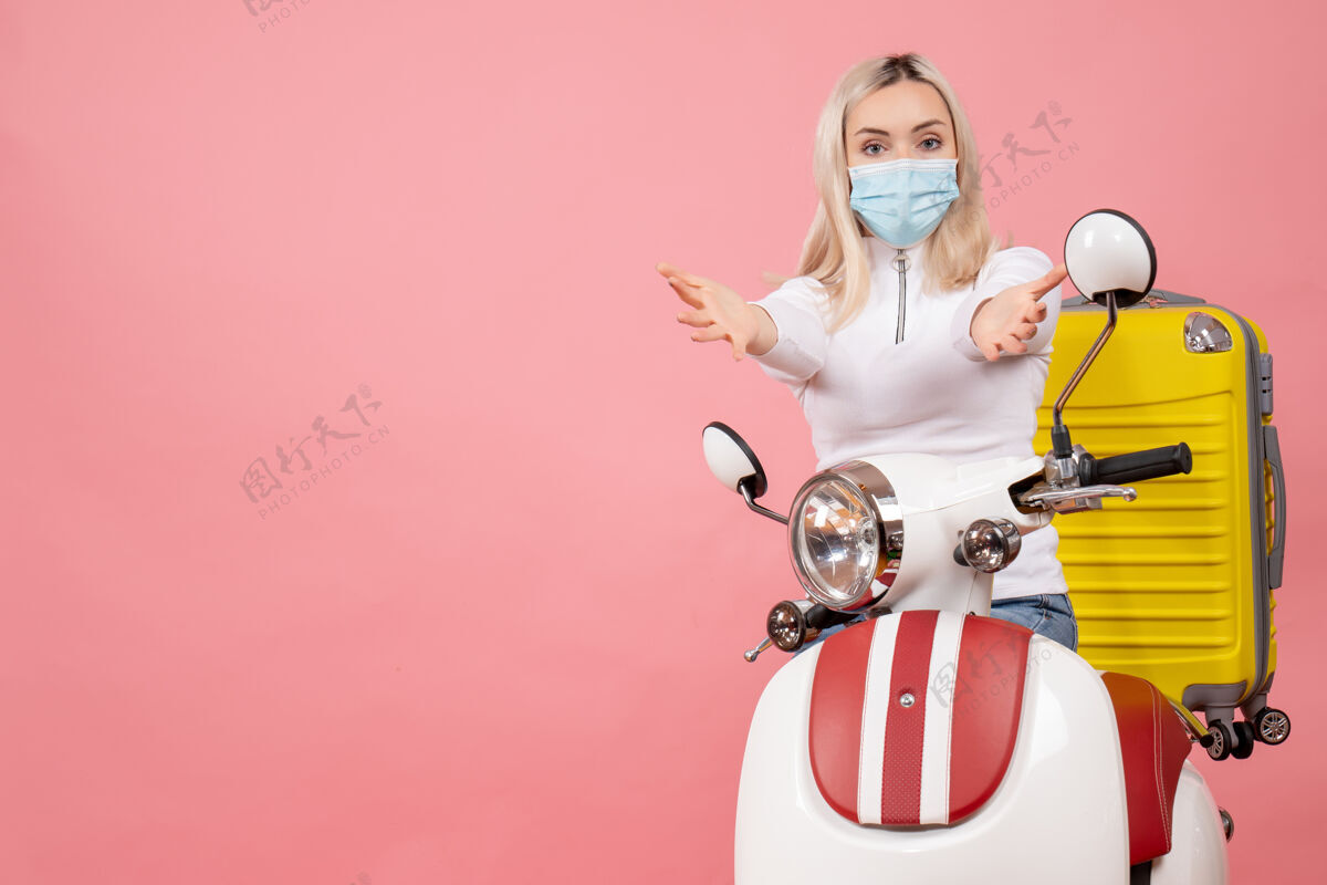 小姐前视图：骑着轻便摩托车的年轻女士 手上拿着黄色的手提箱伸手手快乐