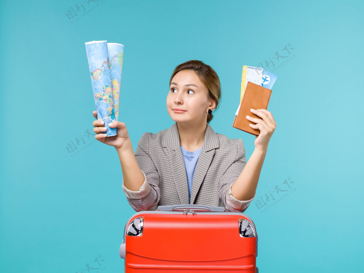 机票前视女在度假持地图钱包和机票上蓝色背景飞机远航海上旅游度假飞机微笑钱包