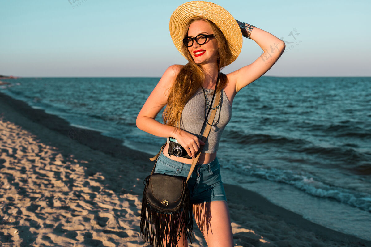 微笑美丽的金发女人戴着草帽在海边散步的户外夏日形象放松乐趣人