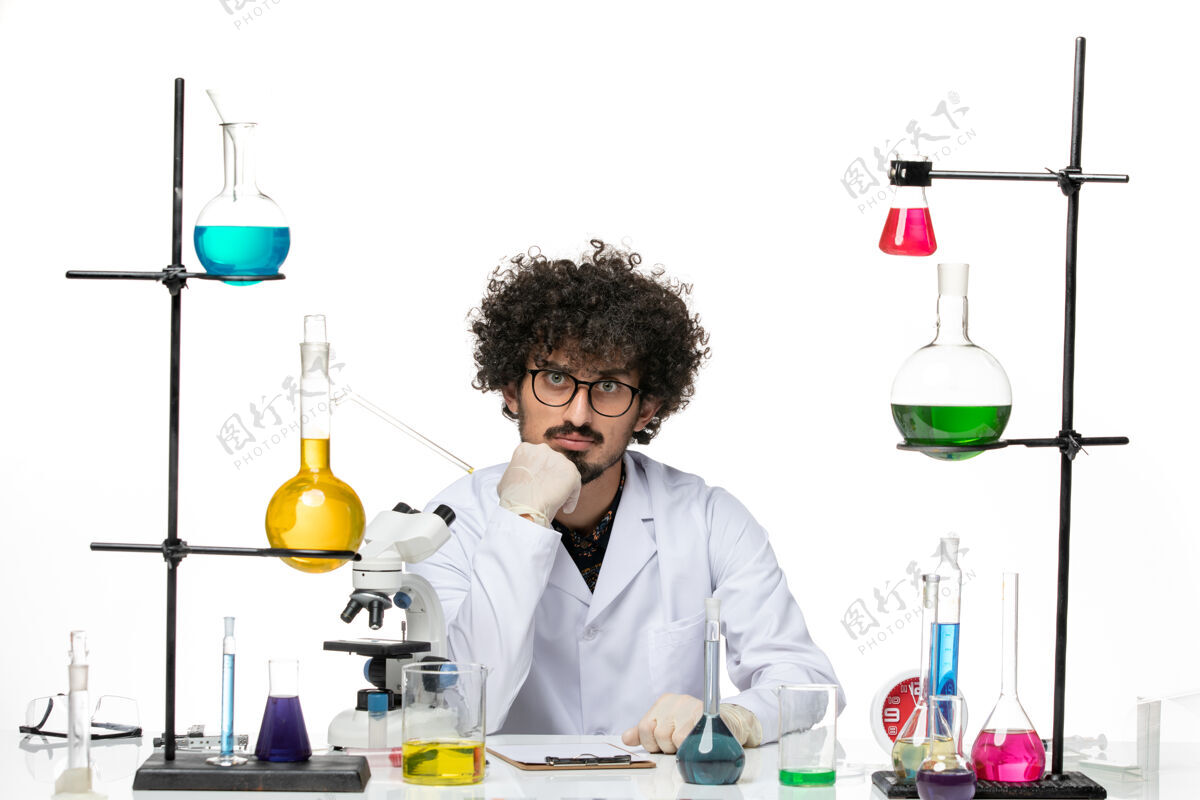 外套前视图穿着医疗服的疯狂男科学家坐在白色空间上 全神贯注地看着注意实验室科学