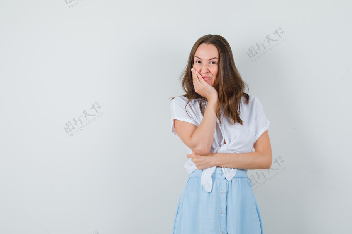 手一位年轻的女士 穿着白衬衫 蓝裙子 脸靠着手站着 看上去很犹豫脸站肖像