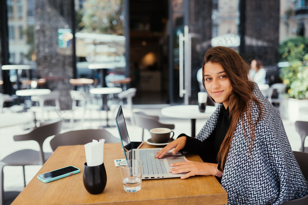 体验一位年轻漂亮的女士在便携式笔记本电脑上工作 迷人的女学生坐在咖啡馆里用上网本培训工作区域