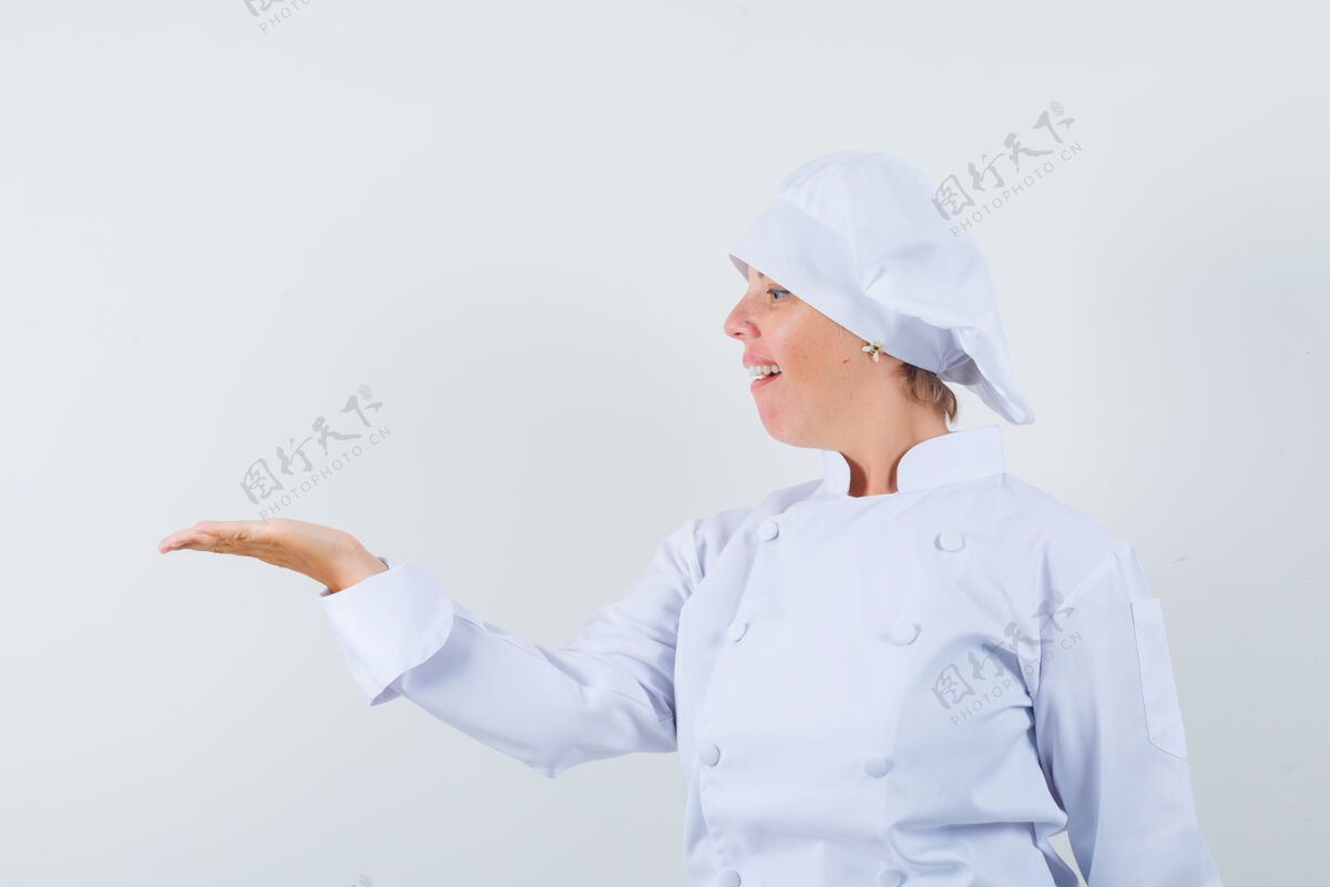 自豪穿着白色制服的女厨师看着摊开的手掌 显得很自豪厨师蔓延时尚