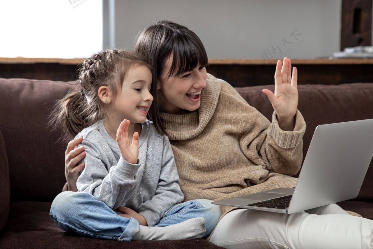 娱乐快乐的一家人看着笔记本电脑屏幕打远程视频电话微笑的妈妈和小女孩在网上聊天沟通家庭孩子