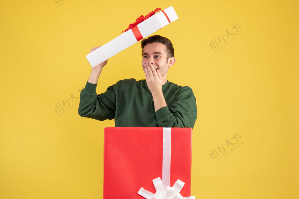 封面正面图快乐的年轻人站在黄色的大礼盒后面 带着盒盖爱国者站着礼品盒