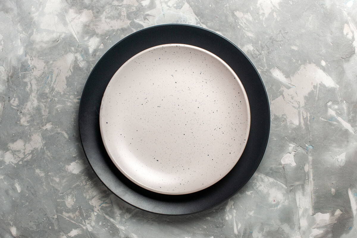 器具黑色圆形空板顶视图 灰色表面上有白色板煎锅饮料锅