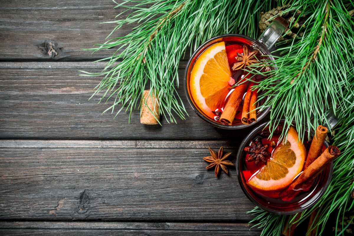 橘子在一张乡村的桌子上用香料搅拌的葡萄酒潘趣圣诞树温暖
