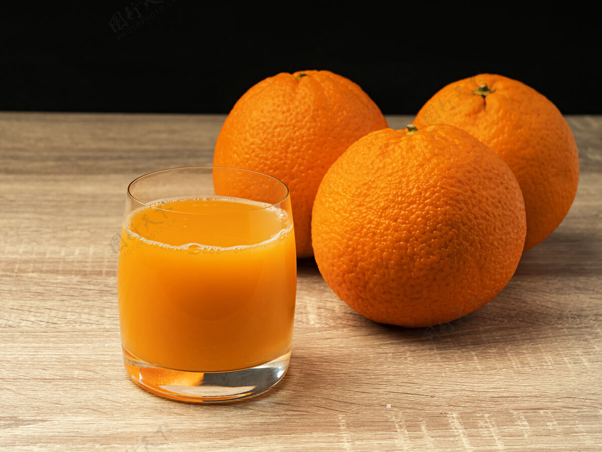 桌子放着橙汁和橙子的玻璃杯放在一张灰色的木桌上木板特写自然