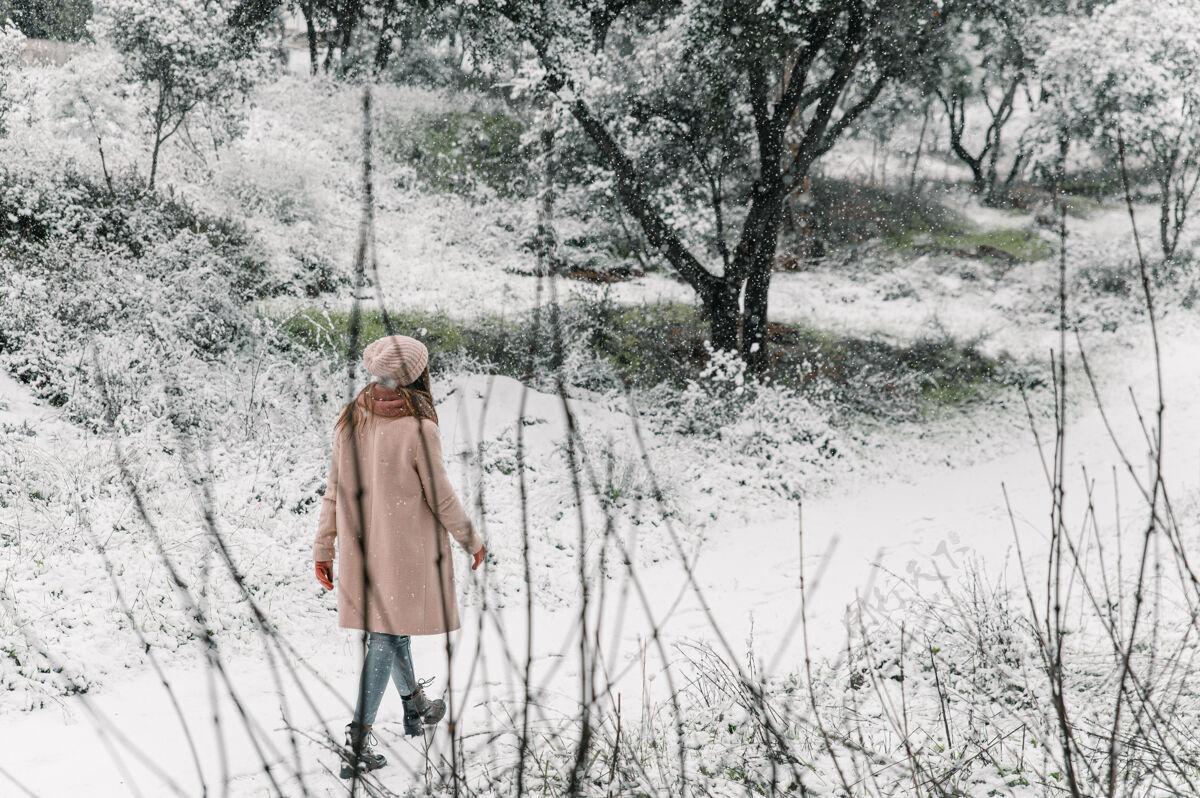 周末穿着暖和外套 戴着帽子的无忧无虑的女人 一边在森林里的小路上散步 一边在冬天享受大自然帽子时尚寒冷