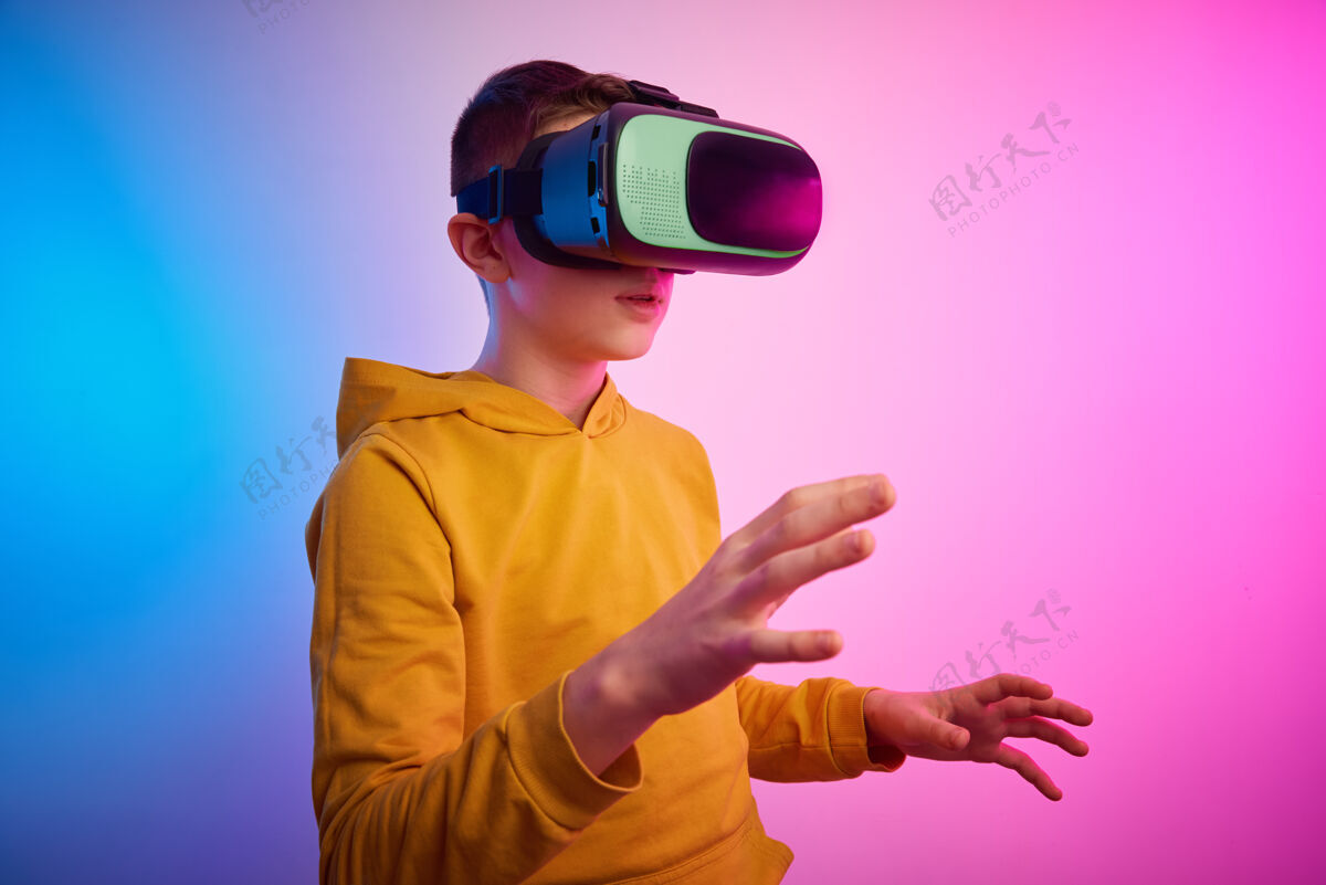 乐趣彩色背景上戴着虚拟现实眼镜的男孩未来科技 虚拟现实概念数据头盔男孩