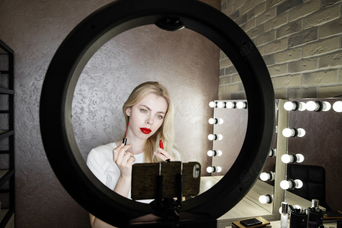 互联网一位年轻女子在美容工作室对着镜子用红唇做亮丽妆容女士魅力生活方式