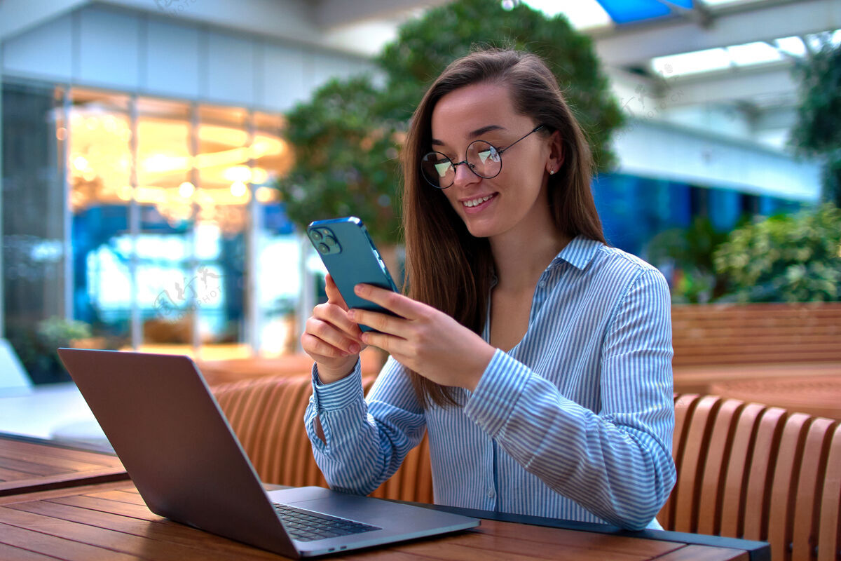 企业家现代休闲聪明的女商人使用电话和笔记本电脑远程在线工作在公共场所专业人士浏览自由职业者