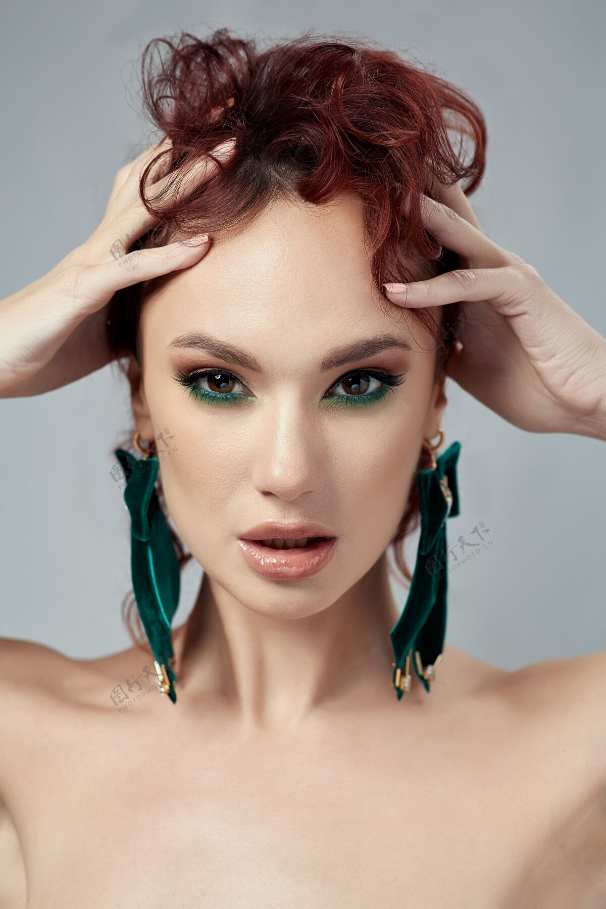 肖像美丽的红头发女人化妆和绿色耳环风格光滑发型