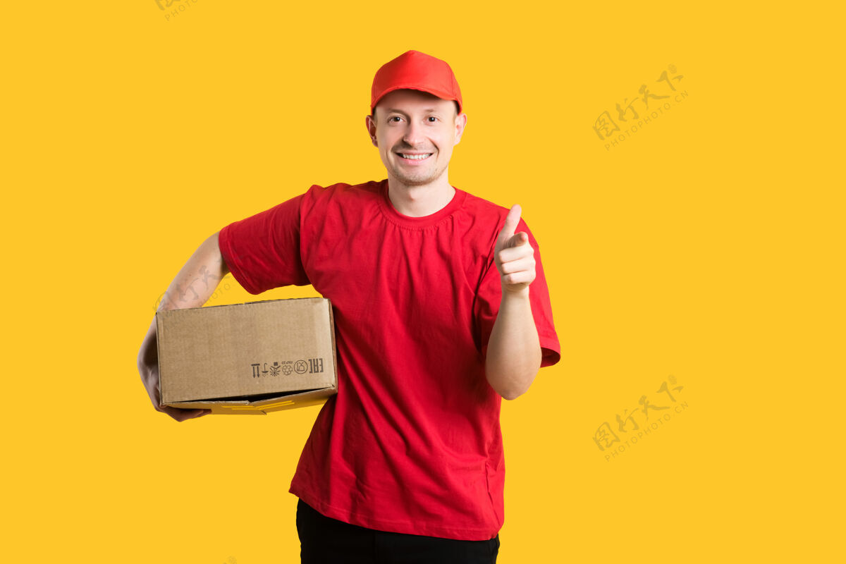 纸板快递员穿着红色t恤 戴着帽子 手里拿着一个黄色的纸板箱盒子男人信使