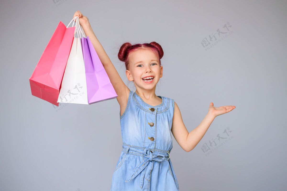 商店满足折扣快乐的小女婴微笑着拿着纸购物袋生日销售购物狂