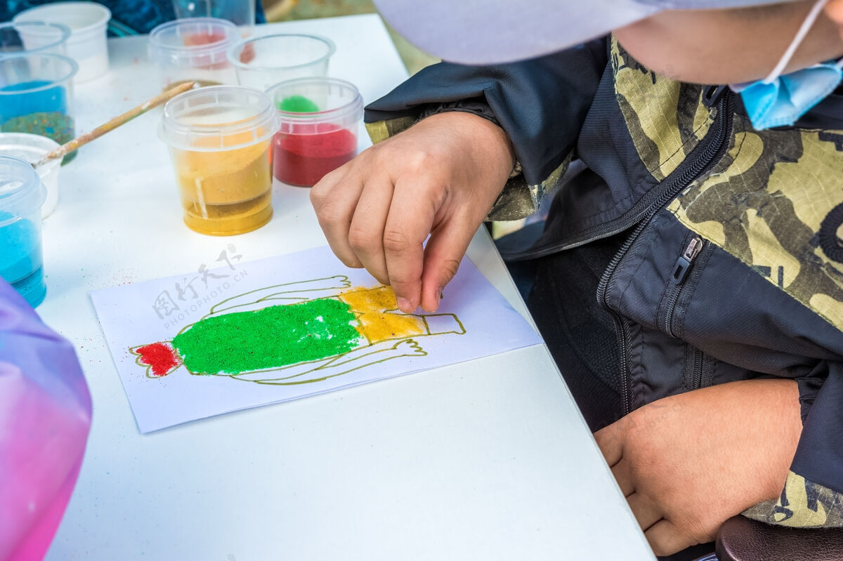概念一个孩子在公园的露天用彩色的沙子画画图片创意智力