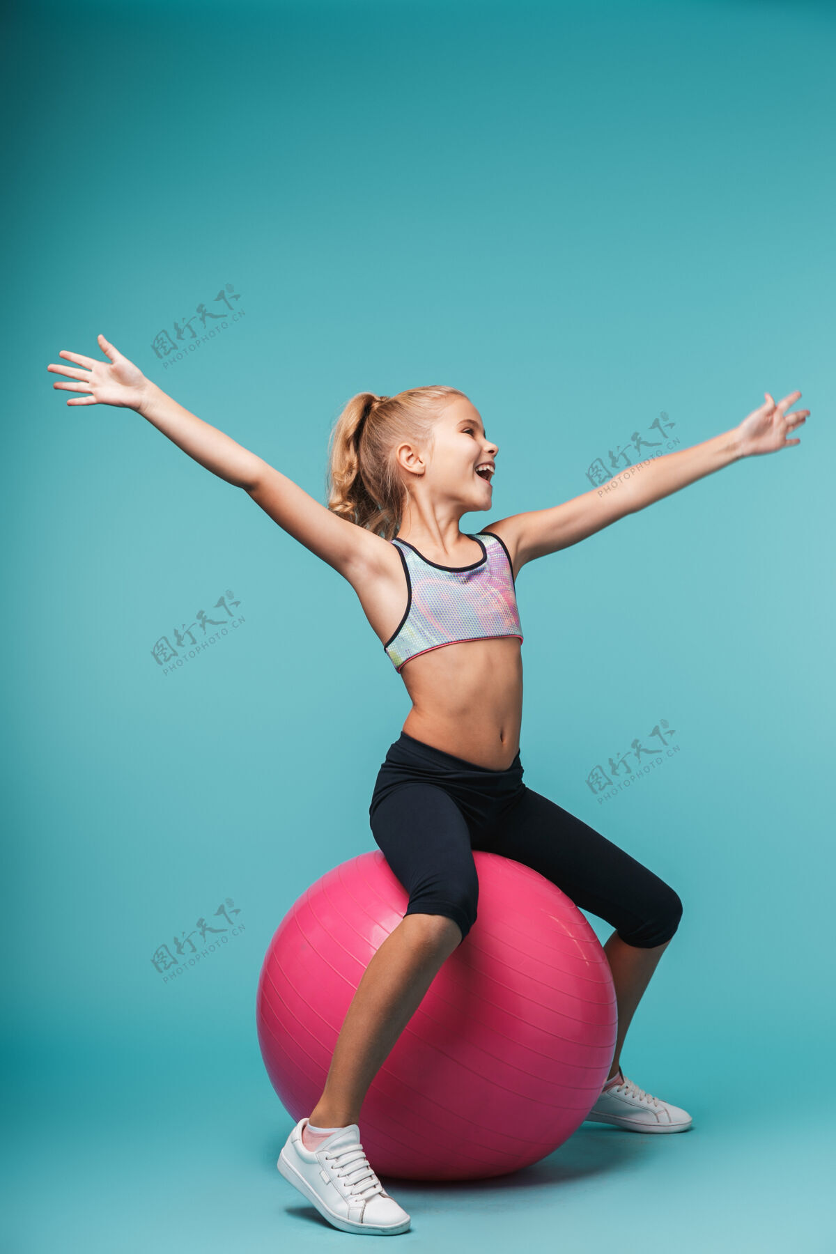 球快乐的小女孩穿着运动服和健身球隔着蓝色的墙做运动孩子运动体操