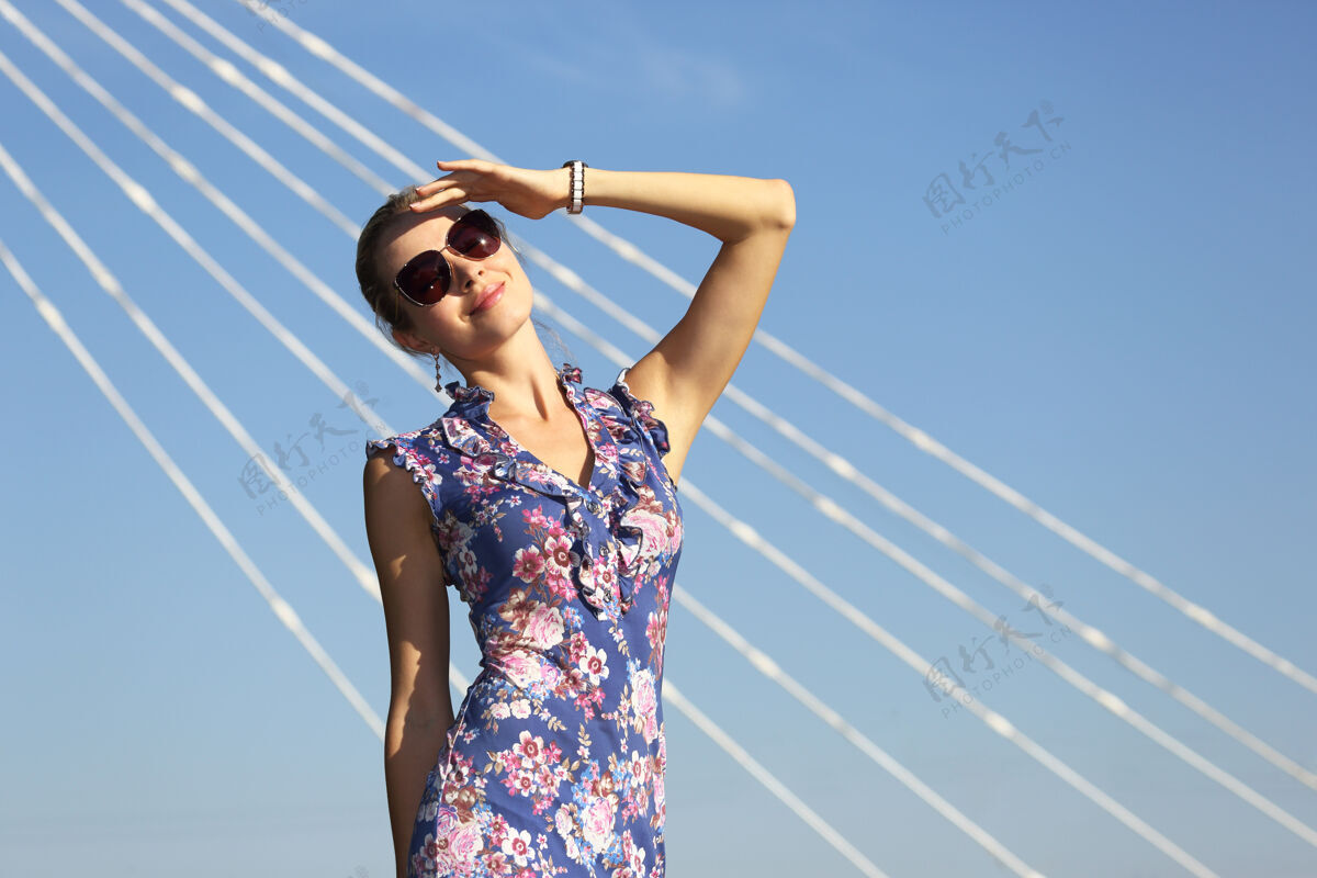 商务女性年轻漂亮的女人戴着太阳镜看着蓝天上的太阳华丽生活方式手