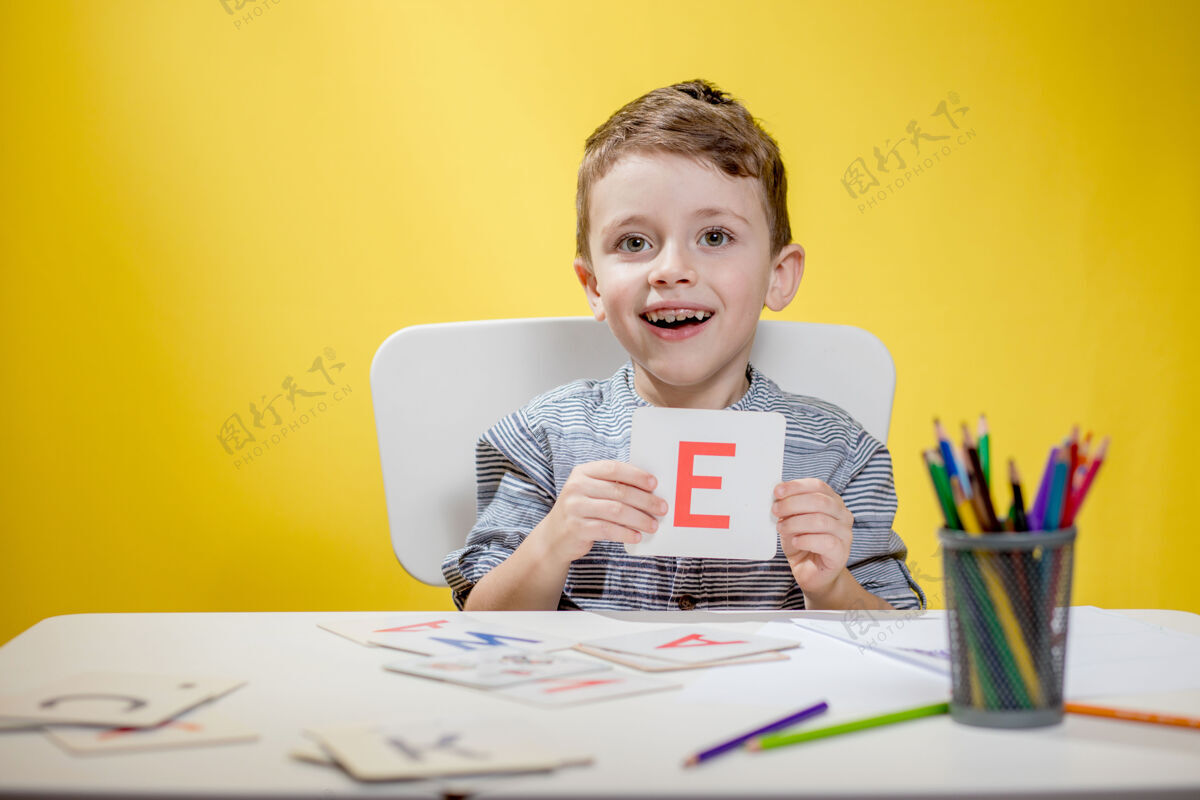 教育快乐微笑的学前班小男孩在家里展示信件做作业学习老师阅读