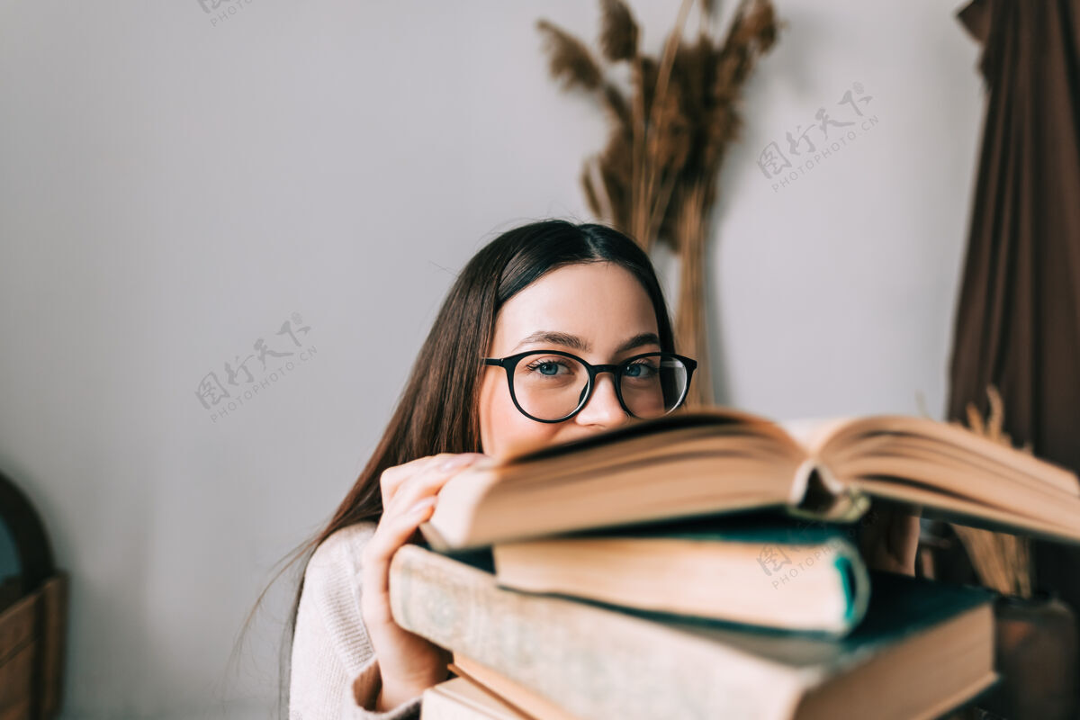图书馆戴眼镜藏在书后面的年轻白人女大学生画像教育人年轻