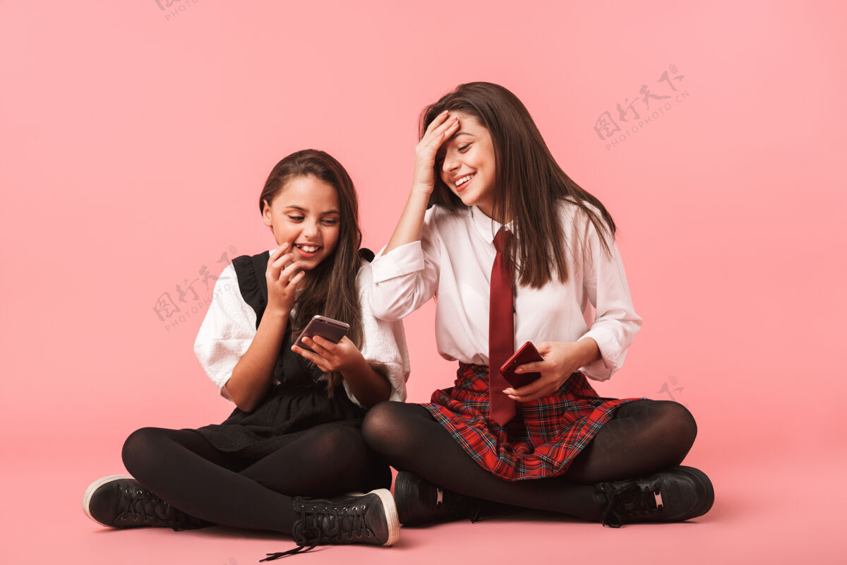 女学生身着校服的女孩微笑着用手机拍照 坐在隔着红墙的地板上黑发室内奥本