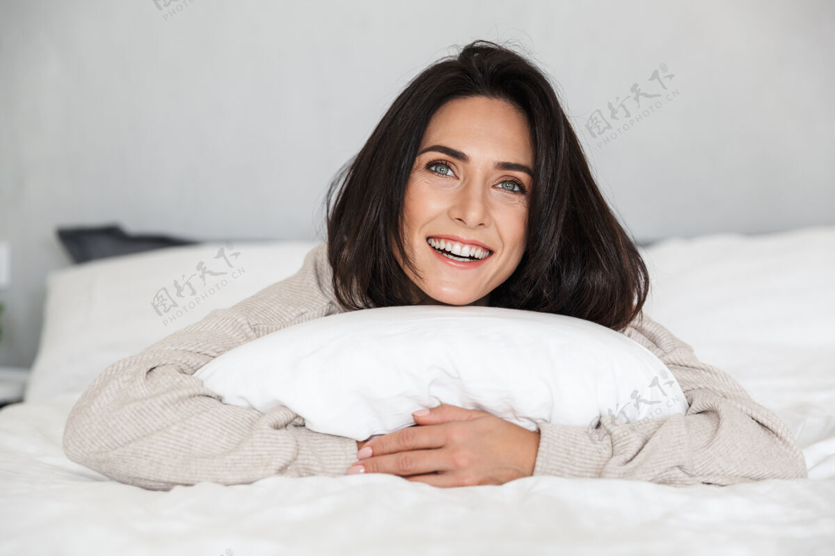 谎言图为30多岁的黑发女子在家中穿着白色亚麻布躺在床上大笑满足中年白种人