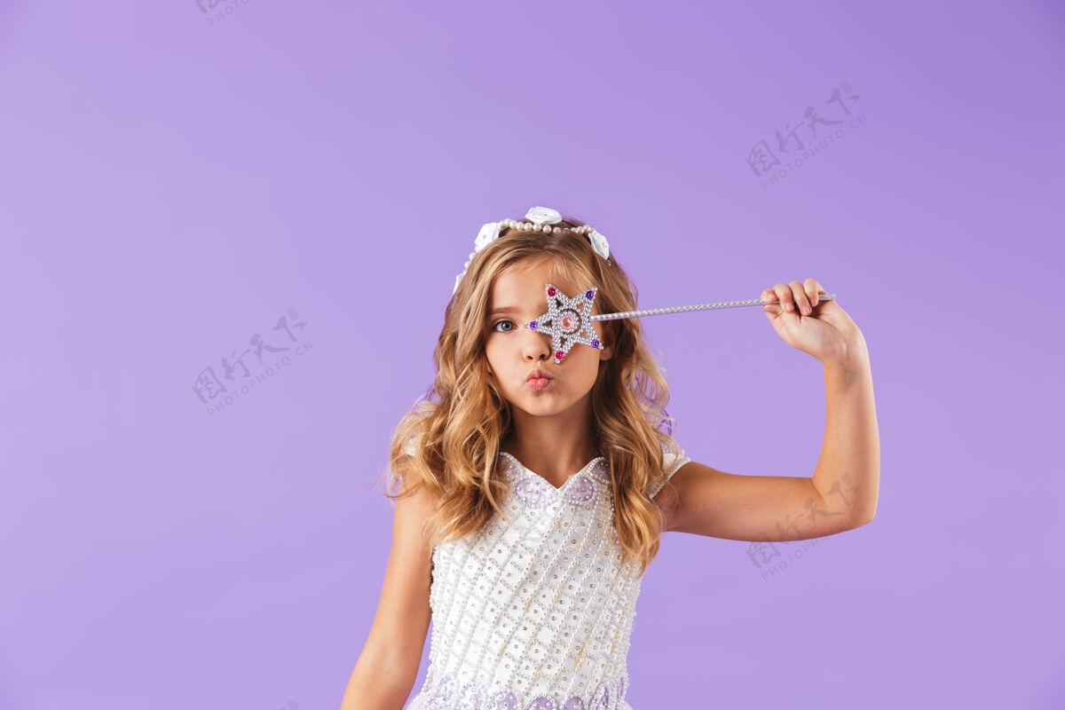 穿一个微笑的可爱女孩的肖像 穿着公主裙 隔着紫罗兰色的墙 手里拿着魔杖表情愿望魔杖