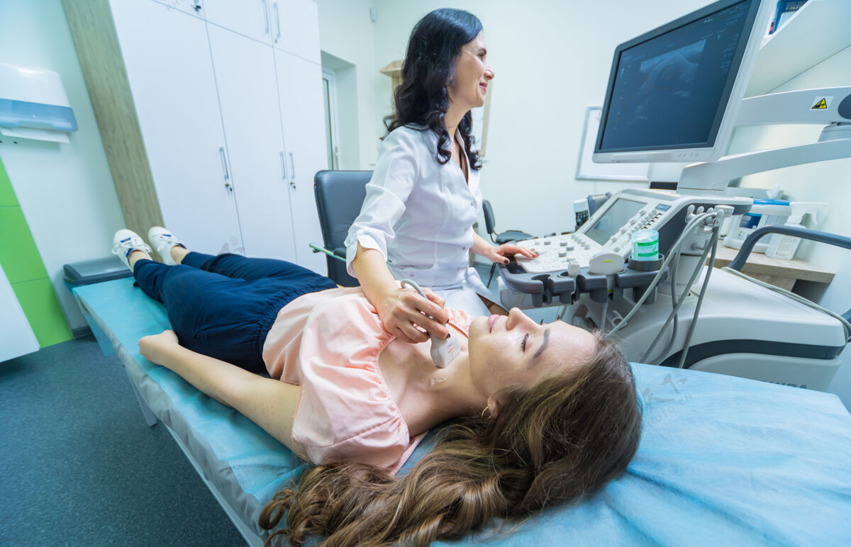 测试医生用超声波扫描仪检查一个女人的甲状腺喉咙医疗颈部