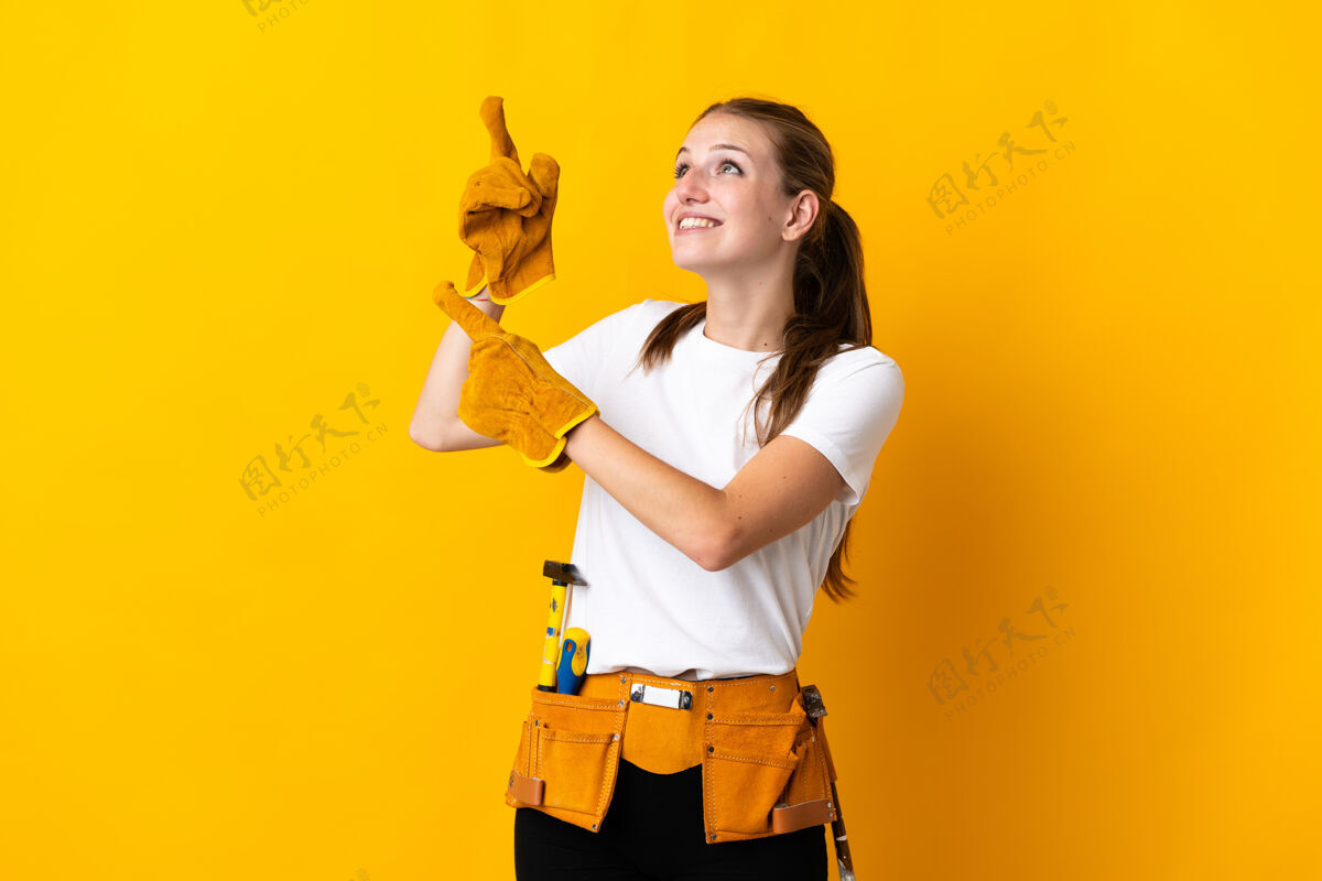 修理年轻的女电工隔离在黄色的背景下用食指指着一个伟大的想法工人女人工匠