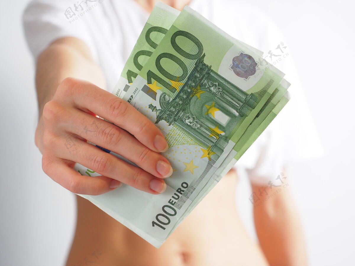 欧元在女性伸出的手上 100欧元比尔那个女人伸出手来钱那个财富的概念 偿付能力模糊背景.焦点在钞票上手钞票储蓄