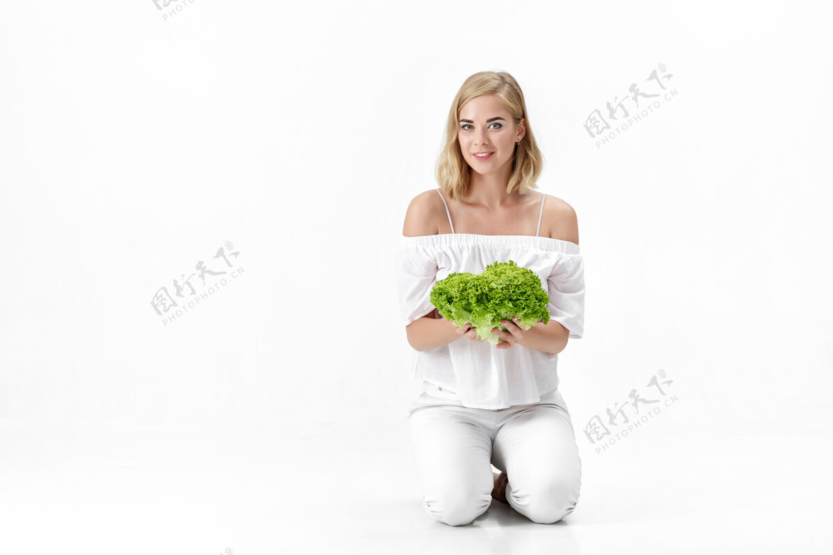 脸一个穿着白衬衫的金发美女拿着一份新鲜的蔬菜沙拉背景.健康还有节食营养模特微笑