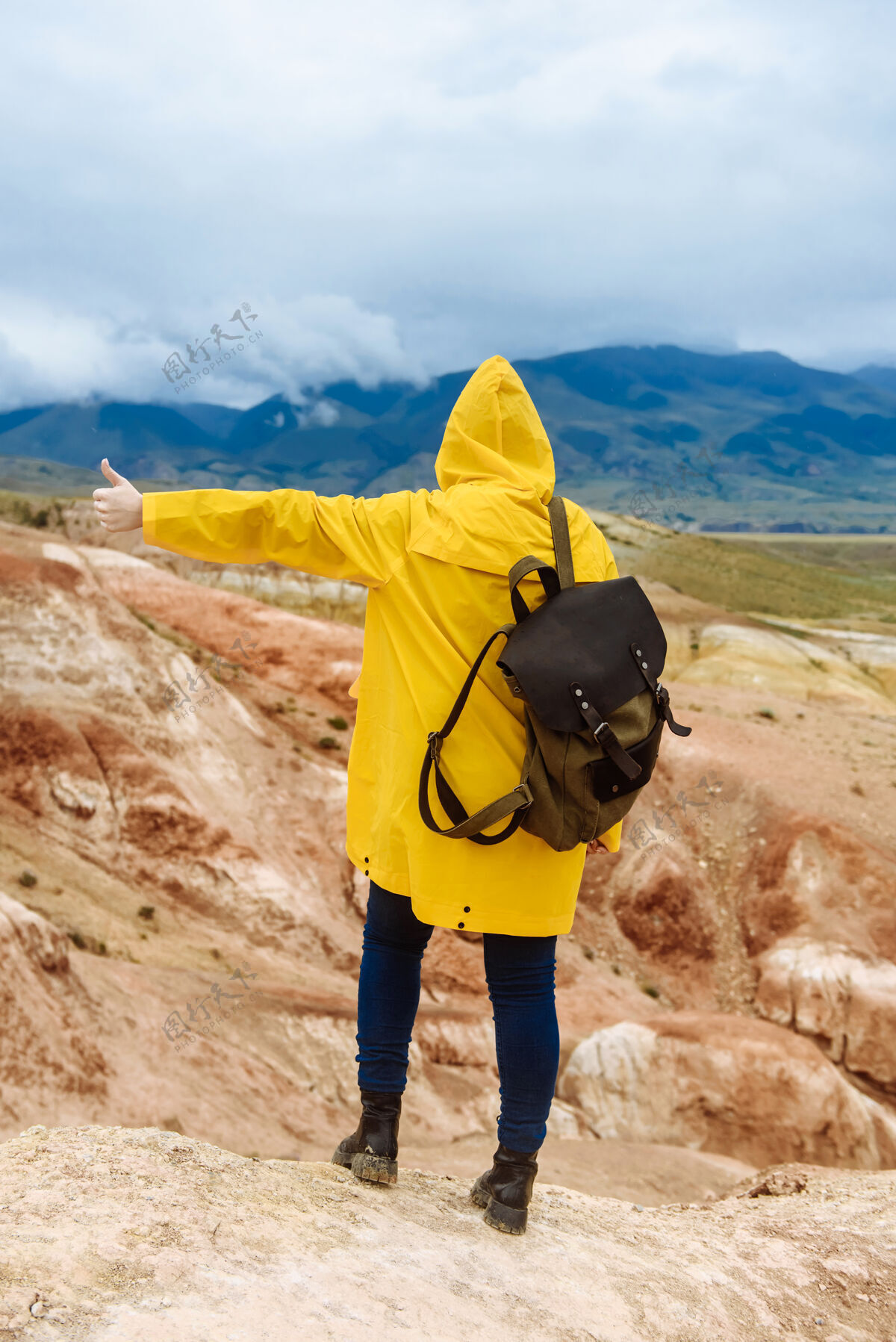 山穿着黄色雨衣背着背包的徒步女孩徒步旅行者旅行者游客