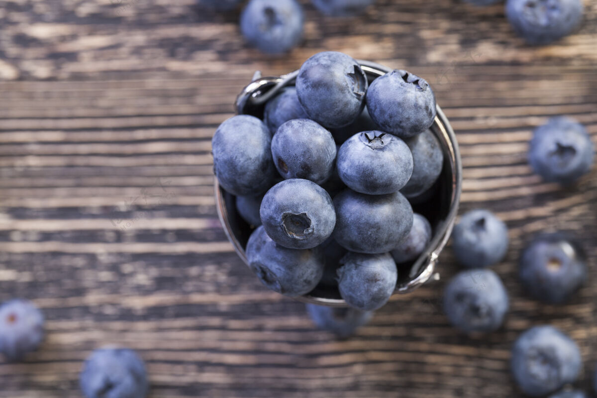 可口蓝色的大蓝莓散落在桌子上 躺在桶里果汁桶叶子