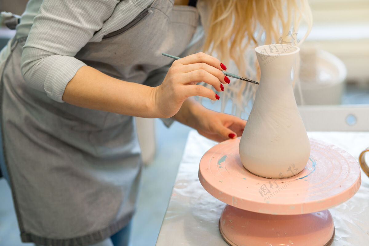 专业美丽的年轻女子在陶艺作坊里画陶罐商业手工形式