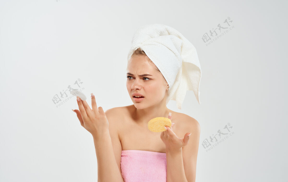 青少年头上戴着毛巾的女人手里拿着一块海绵美容皮肤模型斑点预防问题