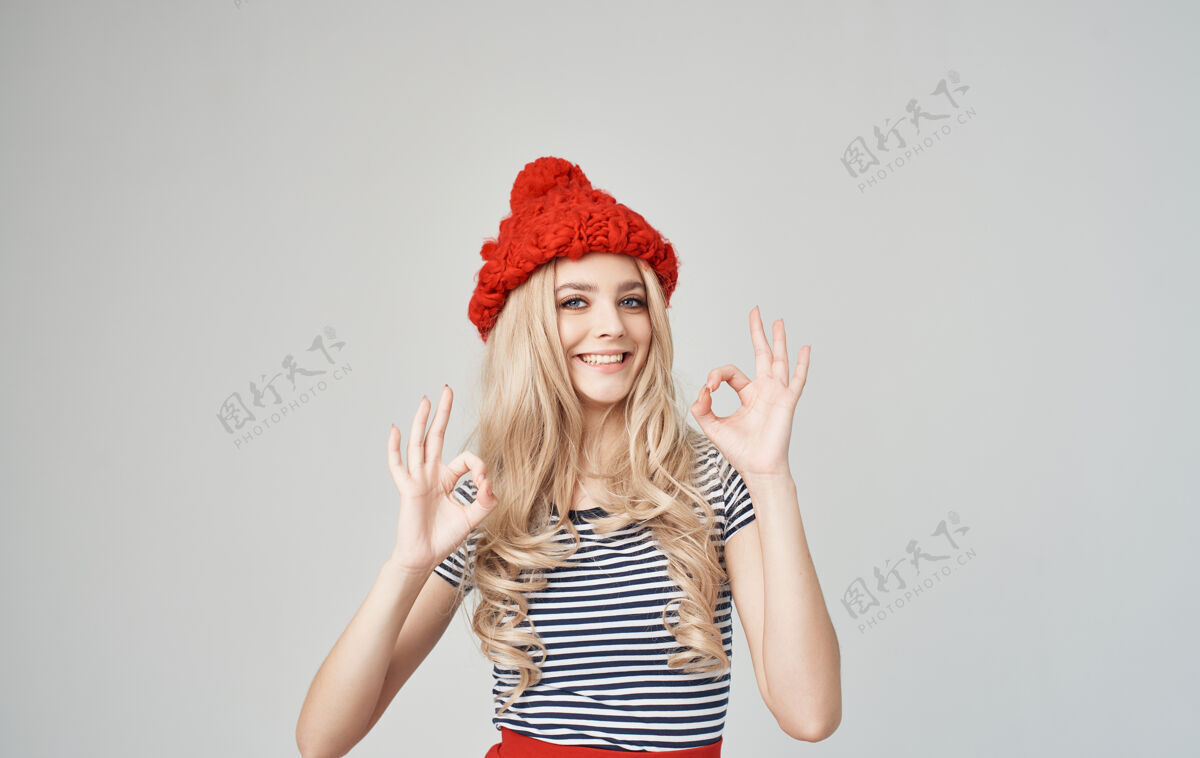 女人穿着条纹t恤和针织帽子的时髦金发女郎用手模仿空间年轻青少年户外
