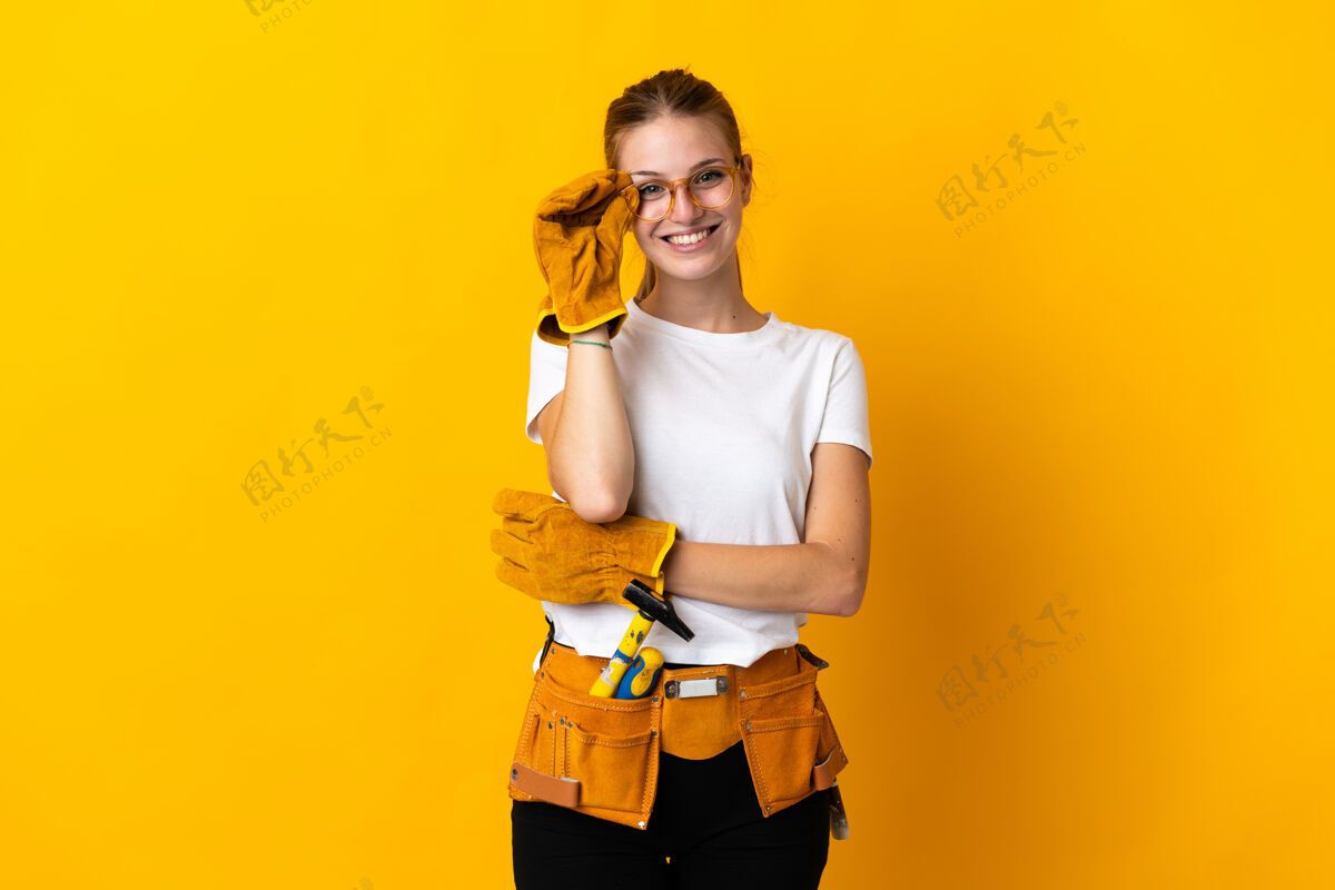 车间年轻的电工女戴着眼镜 在黄色的背景下与世隔绝 快乐微笑快乐工匠