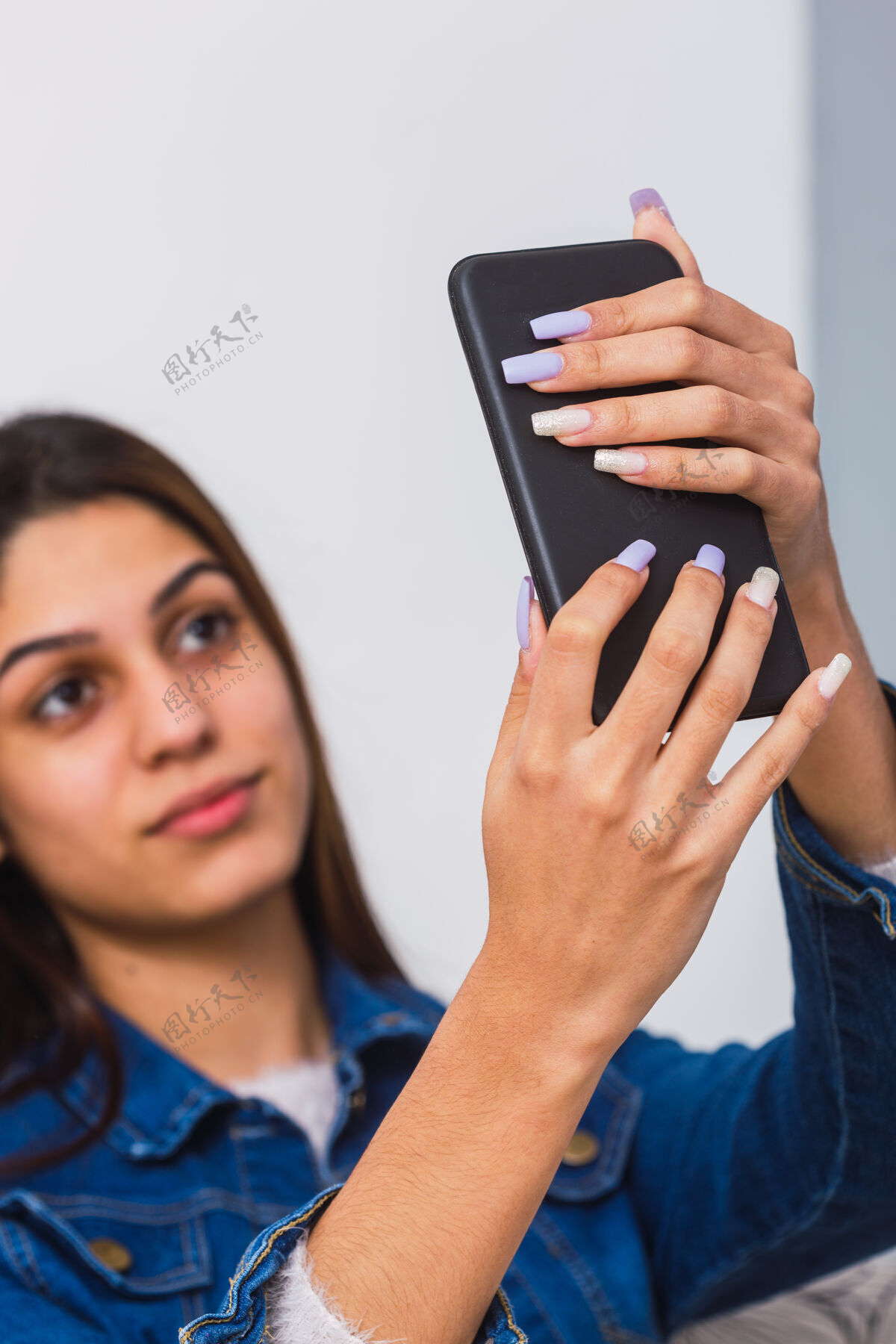 可爱一个年轻的少女在自拍的时候拿着一个小手机 一个长指甲的年轻女人的肖像电话脸肖像