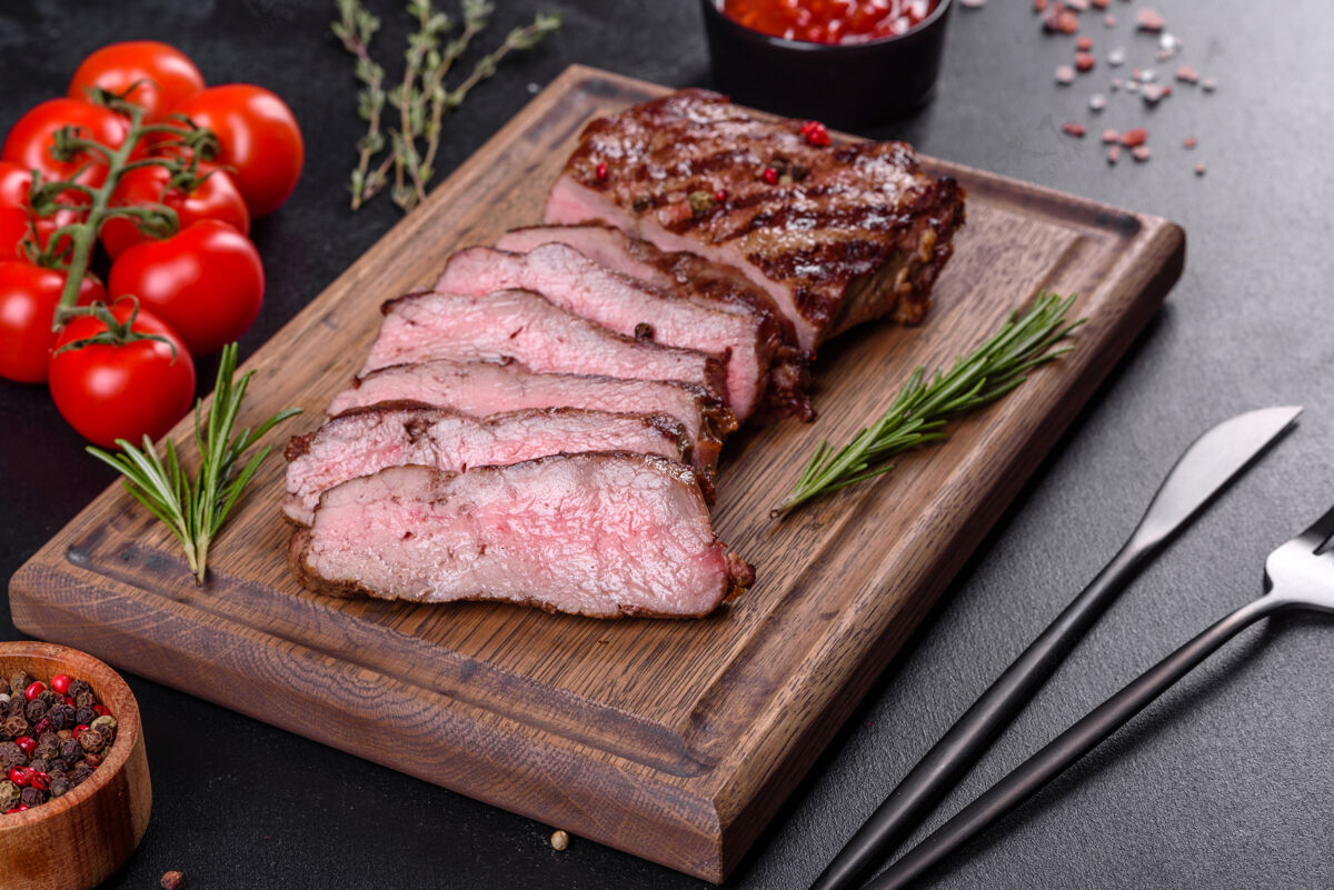 晚餐新鲜多汁美味的牛排 放在深色烤箱里背景.肉用香料和香草做的菜烹饪牛排木板