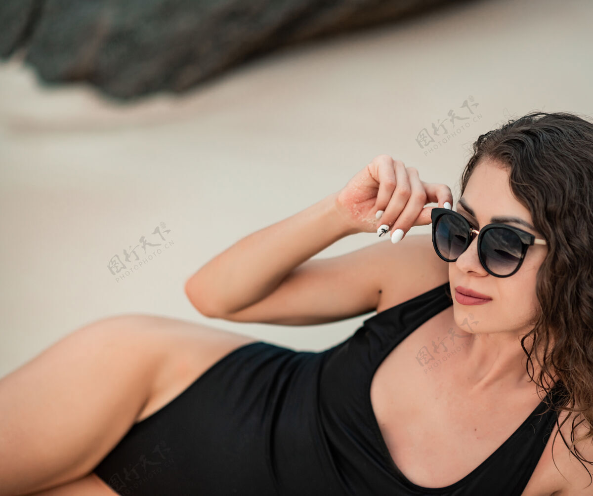 海边优雅的女人 留着长长的头发 穿着黑色豪华比基尼 在沙滩上放松海滩夏天假期躺下户外泰国