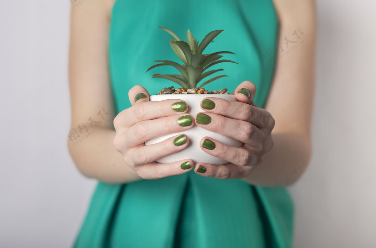 白色背景雌性手持绿色植物大麻女人穿着绿色的衣服 戴着绿色的指甲环境生活小