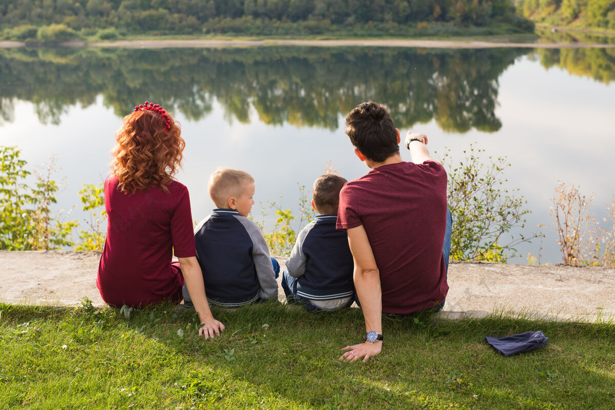 父母童年和自然的概念-家庭与小儿子坐在绿色的草地上女人男人家庭