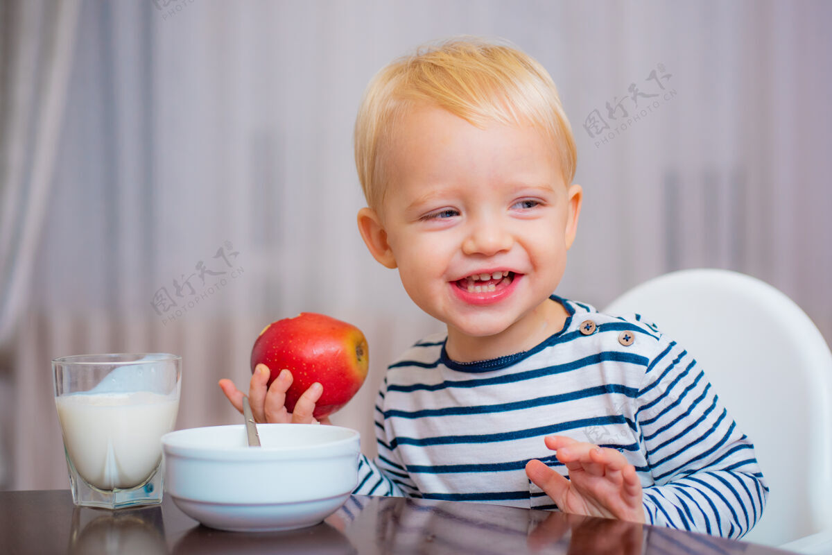 营养可爱的蹒跚学步的孩子正在吃饭 手里拿着一个苹果 微笑着儿童小热量