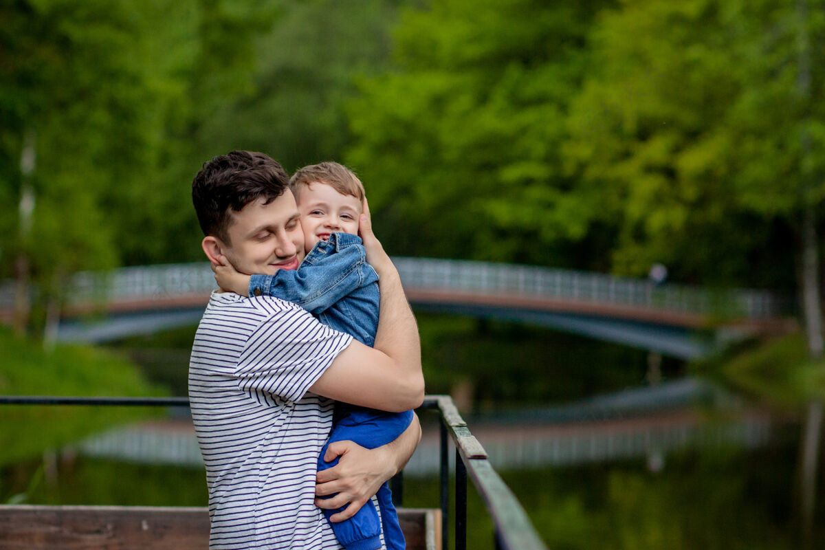 秋天年轻的父亲和他笑容满面的儿子在公园里 拥抱着 享受着一起的时光 庆祝父亲节父亲一起男性