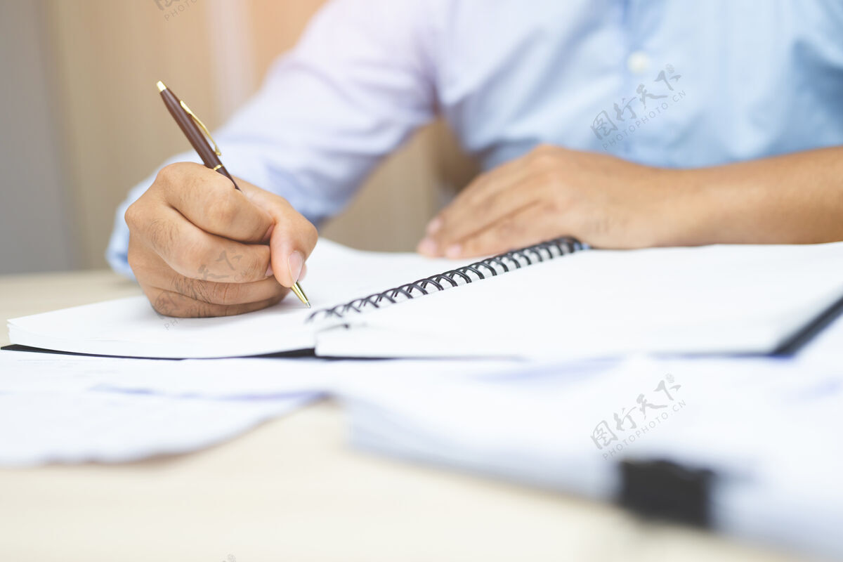 笔记本电脑男手拿笔写在笔记本上经理室内工作