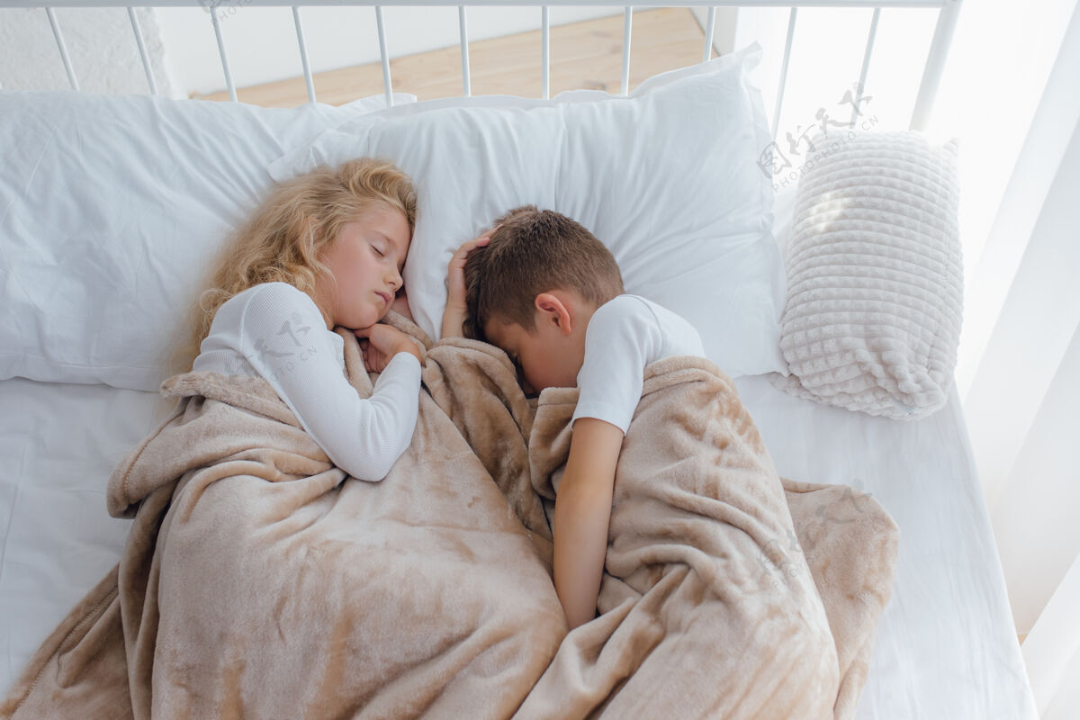 枕头两个孩子睡在婴儿床上 男孩和小女孩睡在床上 顶视图困倦男孩孩子