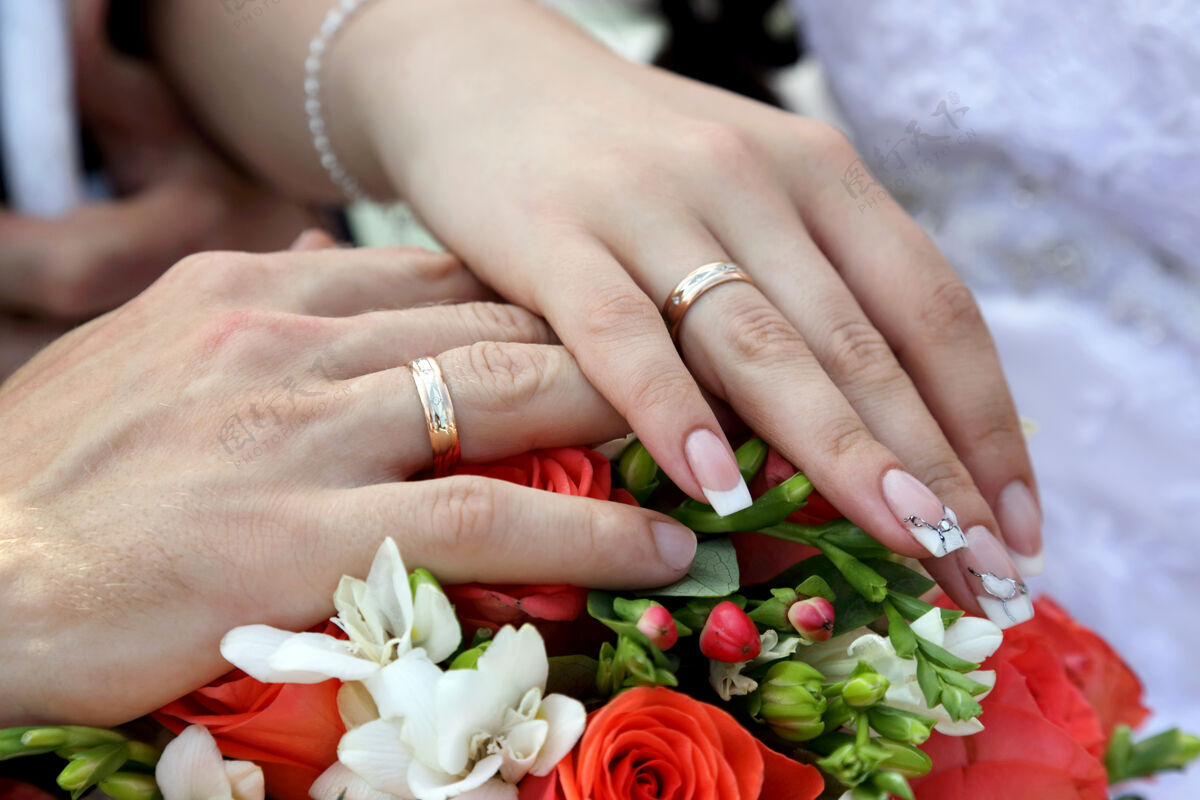 符号新郎和新娘的手放在婚礼花束的背景上触摸新娘花