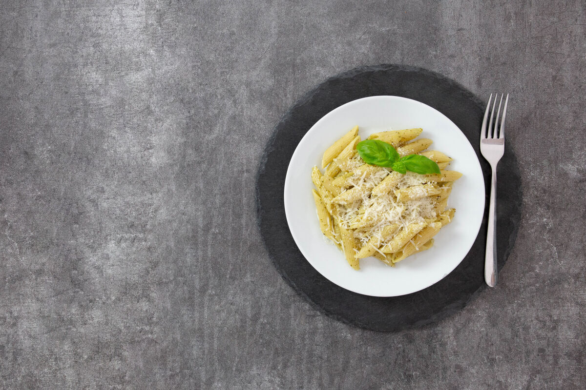 美味传统的意大利潘尼面食 配香蒜酱 罗勒和帕尔马干酪 放在深色的石板板上樱桃盘子部分