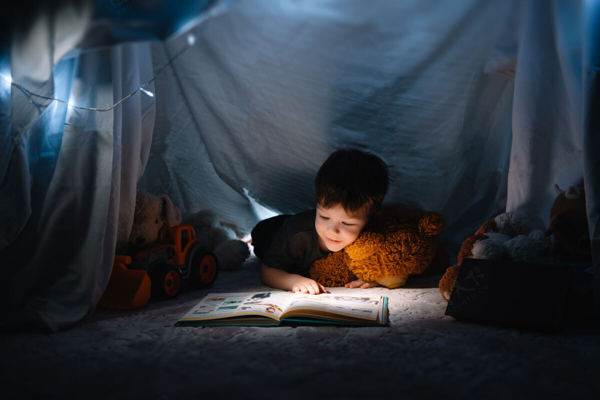 家庭小男孩拿着书 手电筒和泰迪熊在教室里看书帐篷前去睡觉玩耍熊隐藏